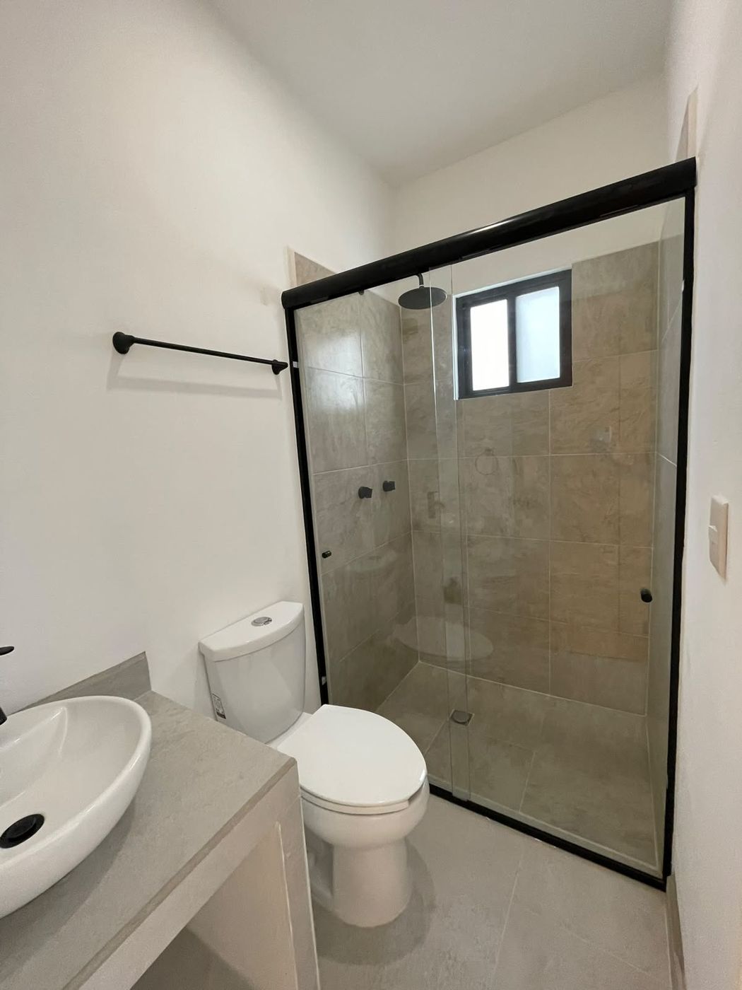 Baño con cancel corredizo negro y lavabo de sobreponer