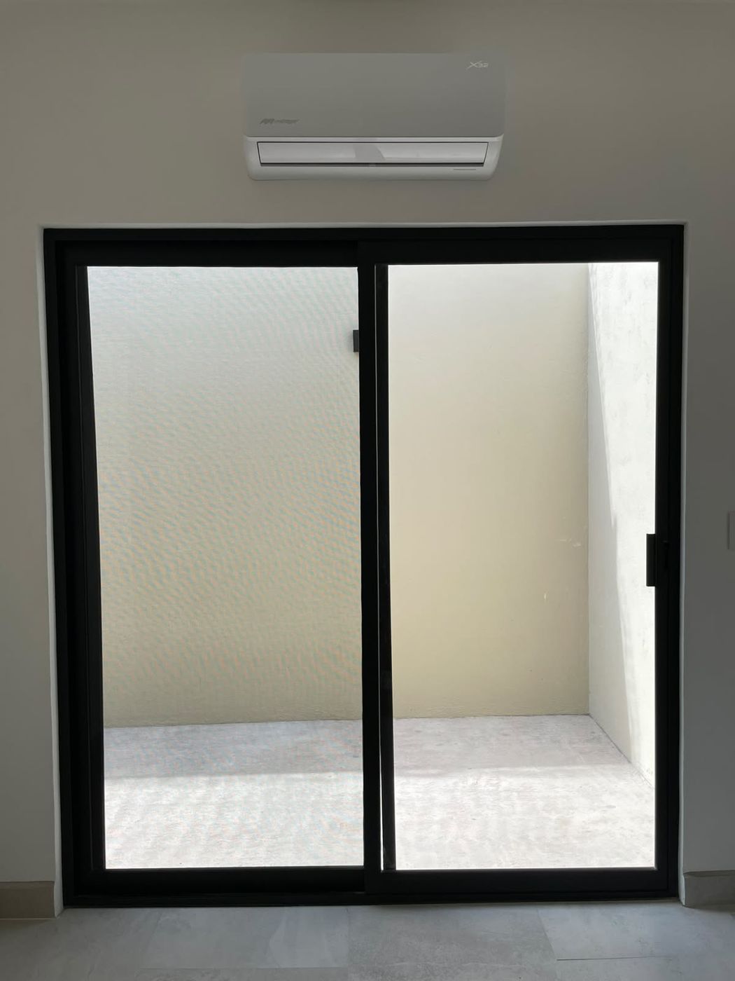 Puerta corrediza de aluminio negro hacia un patio interior